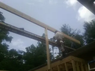 Carpenter setting a ridge beam over a new addition frame — Ice Dam Removal by Roofing Brothers in Electric City