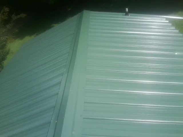 New green metal panels meeting at the ridge of a roof — Flat Roof Repair work by our crew in Electric City
