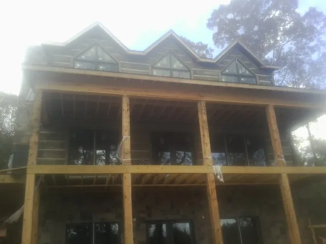 Dormers and porch framing on a large log home under construction — Roof Coating work by our crew in Electric City