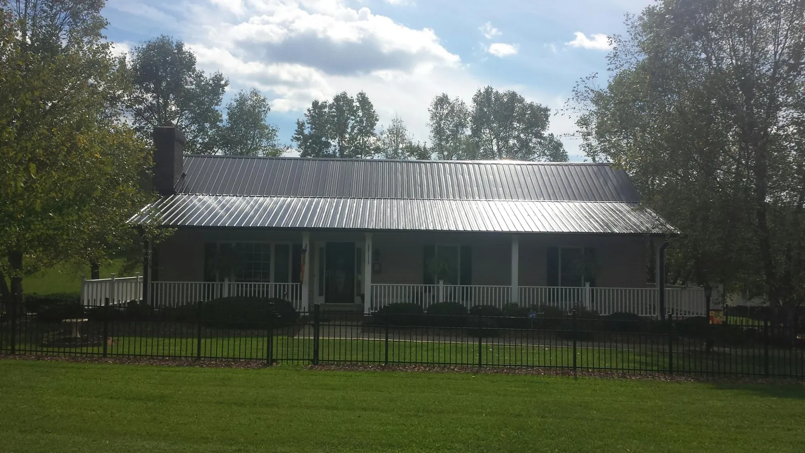 Gray metal roof on a brick ranch with a full width front porch — Gutter Guard Installation work by our crew in Electric City