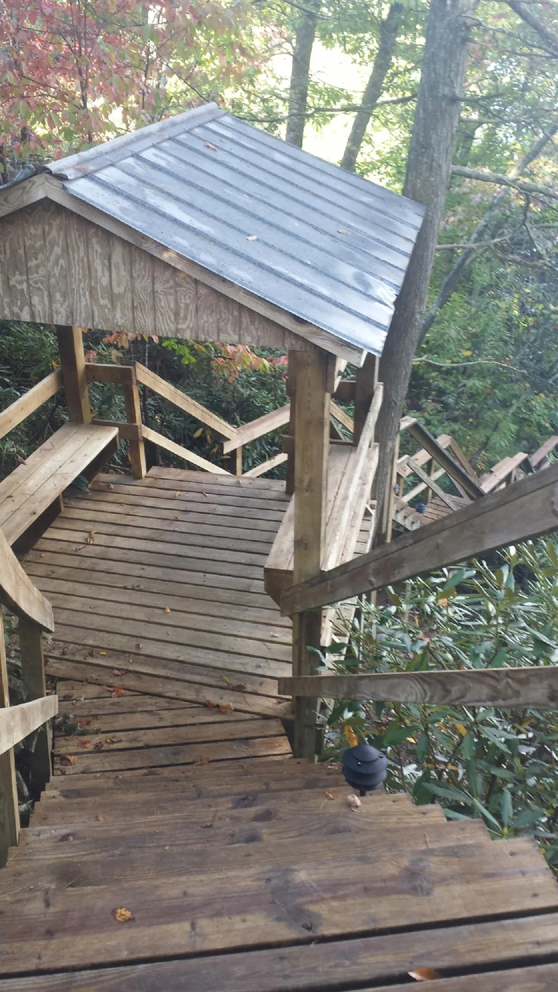 Metal roofed shelter over wooden steps on a wooded walkway — Skylight Repair & Installation work by our crew in Electric City