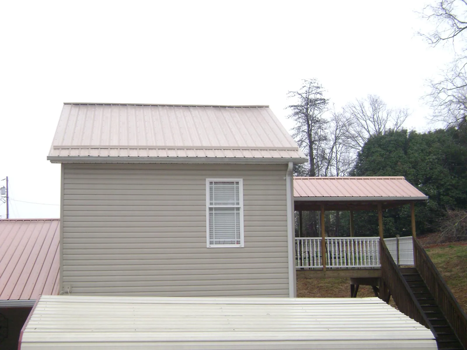 Tan metal roofs on a two story addition and attached porch, from a Roof Replacement job in Electric City