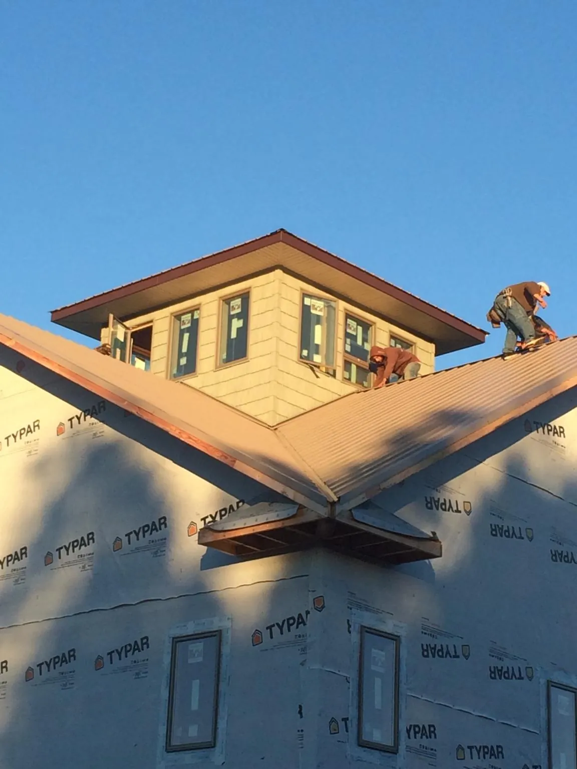 Roofers working around a rooftop cupola on a new metal roof at sunset — Roof Waterproofing in Electric City by Roofing Brothers